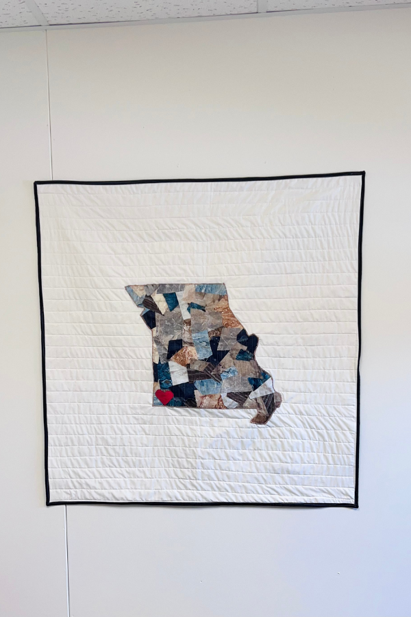 Quilted wall art hanging on a wall in an office. 