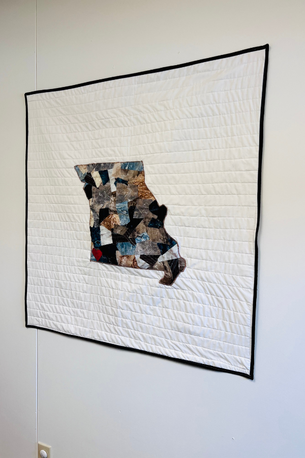 Quilted wall art hanging on a wall in an office.