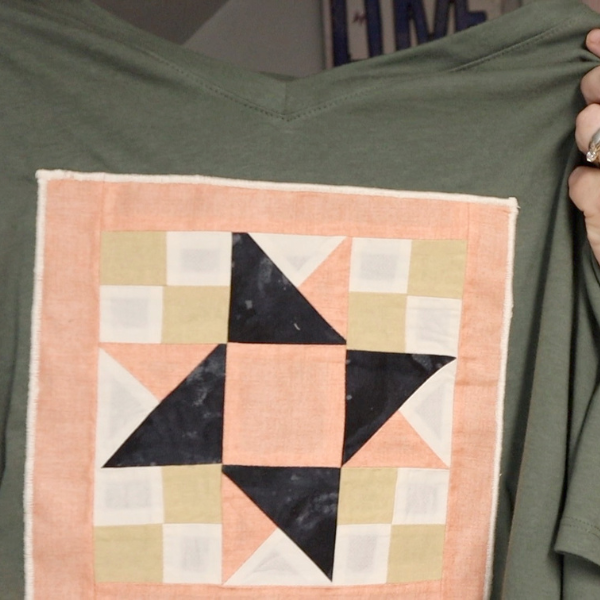 A sewing machine stitching the quilt block onto the shirt
